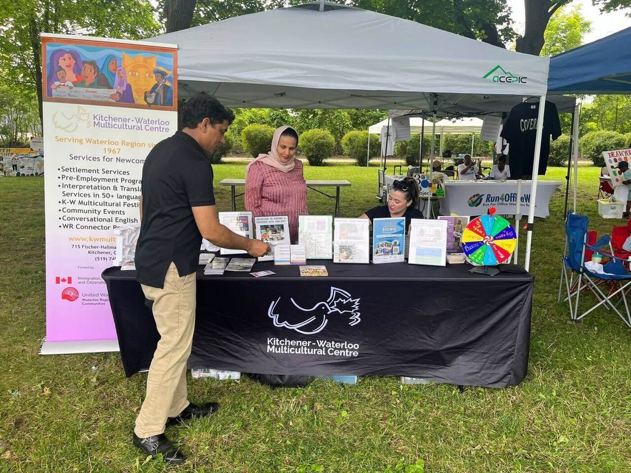 Nazim Shah speaking with community representatives at the Kitchener-Waterloo Multicultural Centre booth
